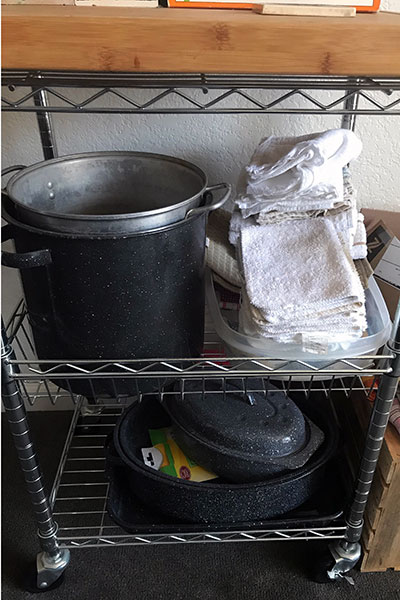 Bottom shelf of microwave stand with stockpots and other items