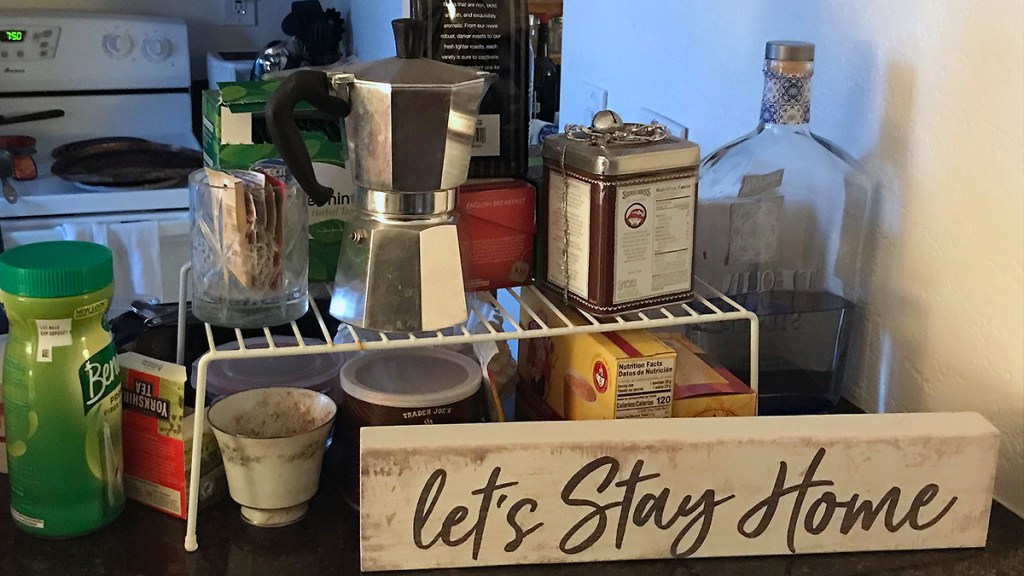 Sign reading "Let's Stay Home" in front of kitchen items